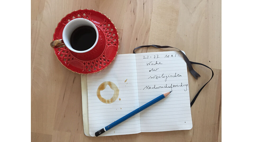 Kaffeetasse, Bleistift und Notizheft mit Schriftzug