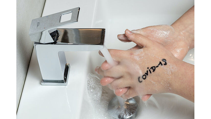 Persond die sich die Hände am Waschbecken wäscht , die die Aufschrift Covid 19 haben