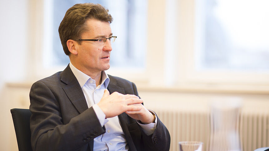 Jörg Flecker im Gespräch, sitzend, mit zusammengelegten Händen