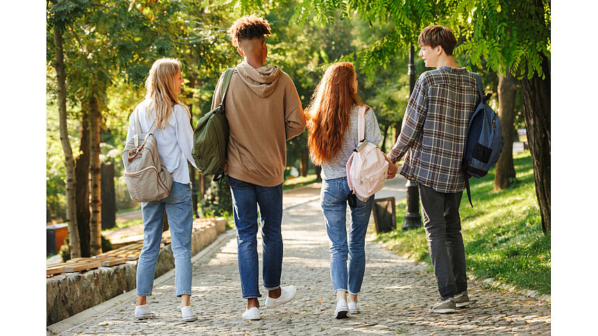 4 Personen spazieren auf einem Parkweg