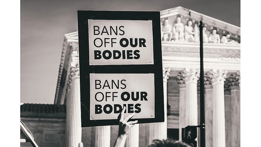 Hand with sign that reads "bans off our bodies"