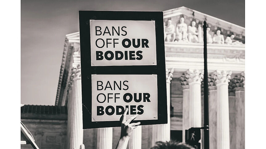 Hand mit Schild, auf dem zwei Mal "bans off our bodies" steht