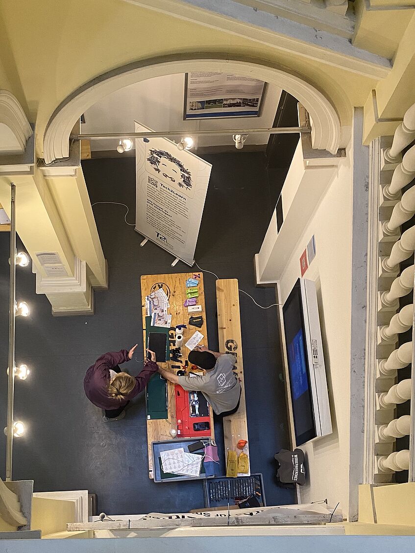 Foto von oben aus dem Treppenhaus von dem Reparaturstand für Laptops und Smartphones 